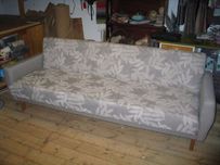 Harmaalla kankaalla verhoiltu sohva