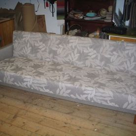 Harmaalla kankaalla verhoiltu sohva